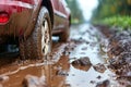 Red car splashing through muddy puddle with leaf stuck in its tire Royalty Free Stock Photo