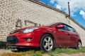 The red car is standing against a brick wall