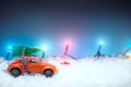 Red car toy carrying a Christmas tree with Christmas lights in t Royalty Free Stock Photo