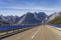 A red car transits on a road between mountains Royalty Free Stock Photo