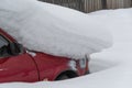 Red car under pile of snow. Unexpected snowfall, danger on road Royalty Free Stock Photo