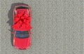 Red car wrapped in a red ribbon bow standing on the paving stones. Expensive gift. Top view. 3D render. Copy space.