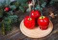 Red caramel apples on sticks on Dark wood background, with Christmas tree branches