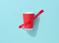 Red cardboard cup glued with red sticky tape to the blue background Royalty Free Stock Photo