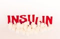 Red cardboard insulin word surrounded by refined sugar cubes on white background, diabetes protection medical concept