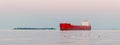 A red cargo ship is sailing on the sea next to the island Royalty Free Stock Photo