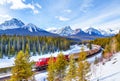 Red cargo train passing through Morant's Curve in the Canadian Rockies of Banff in beautiful snowy winter landscape