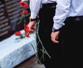 Red carnations in the hands of men in black trousers Royalty Free Stock Photo