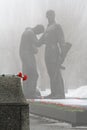 Red carnations lie on a granite cobblestone on the background of the monument to Komsomol members in Volgograd.