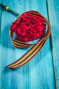 Red carnations and St. George ribbon on wooden background St. George ribbon - the symbol of the great Victory Victory Day
