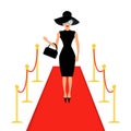 Red carpet and rope barrier golden stanchions turnstile Isolated Woman in black hat, bag, sunglasses waving. Royalty Free Stock Photo