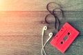 Red cassette tape with earphone over wooden table. top view. Retro or vintage color filtered. Old time concept. Nostalgia concept. Royalty Free Stock Photo