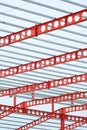 Red castellated beam metal roof structure of large industrial building in construction site against white cloudy sky Royalty Free Stock Photo