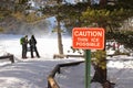 A red caution sign warns hikers of possible thin ice across a frozen lake. Royalty Free Stock Photo