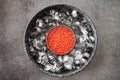 Red caviar in can on ice on grey