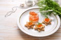 Red caviar with cream and dill on toasted canapes in star shape on a white plate, preparation for a festive holiday buffet on a