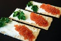 Red caviar on crispy bread with cream cheese and green. Healthy food. Sandwiches with caviar isolated on black background