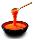 Red caviar dripping from the wooden spoon to the black plate. Protein healthy food Royalty Free Stock Photo