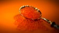 Red Caviar in a spoon. Caviar over orange background. Natural Fish roe, Close-up salmon or trout caviar