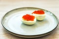 Red caviar stuffed halved eggs traditional Russian snack served on blue grey plate close up