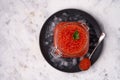 Red caviar to the top of a filled glass jar on a black plate with crushed ice on a black plate with a spoon with caviar Royalty Free Stock Photo