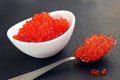 Red caviar in a white plate with a spoon lies on a black background Royalty Free Stock Photo