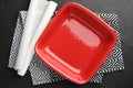 Red ceramic casserole and baking parchment paper on black table, top view Royalty Free Stock Photo