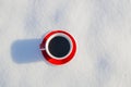 Red ceramic cup of espresso coffee on snow background of a winter landscape