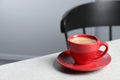 Red ceramic cup with hot aromatic coffee on white table indoors, space for text Royalty Free Stock Photo