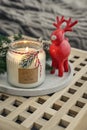 Red ceramic deer and candle in jar with fir tree branches