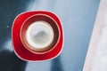 Red ceramic espresso cup placed on a dark table