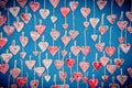 Red, ceramic hearts suspended on hemp strings on a blue background. Valentine`s Day background