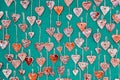 Red, ceramic hearts suspended on hemp strings on a green background. Valentine`s Day background