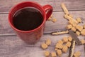 Red ceramic mug with tea, cookie sticks with chocolate and white icing, and pieces of brown cane sugar on a wooden background. Royalty Free Stock Photo