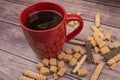 A red ceramic mug of tea, pieces of brown cane sugar, and cookie sticks with chocolate and white icing on a wooden background. Royalty Free Stock Photo