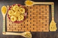 Red ceramic plate and bamboo spatulas with different paste on a bamboo napkin and a wooden background