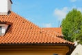 Red ceramic shingles roof with attic windows and chimney against blue sky. Decorative rain gutter. Royalty Free Stock Photo