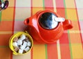 Red ceramic teapot and cubes white sugar and cane sugar isolated on a colored checkered tablecloth, top view. Tea ceremony Royalty Free Stock Photo