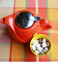 Red ceramic teapot and cubes white sugar and cane sugar isolated on a colored checkered tablecloth, top view. Tea ceremony Royalty Free Stock Photo