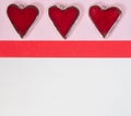 Red ceramic Valentines hearts on a pink and white paper background