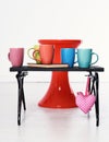 Red Chair And Black Wooden Tray With Colorful Cups And Book On It Sweat Pink Heart On White Background