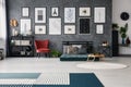 Red chair next to green futon with pillows in grey apartment interior with posters and rug. Real photo Royalty Free Stock Photo