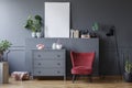 Red chair next to grey cabinet in living room interior with mock Royalty Free Stock Photo