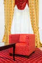 Red chair in the room with vintage red carpet and classic yellow drapes