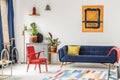 Red chair and royal blue lounge placed in bright sitting room in