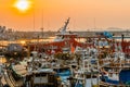 Red charter tour ship behind rows of fishing trawlers moored at port at sunset