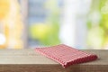 Red checked tablecloth on wooden table over abstract blurred  background. Kitchen interior mock up for design and product display Royalty Free Stock Photo