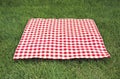 Red checkered gingham cloth on green grass. Picnic towel.Tabletop advertisement design. Food promotion display Royalty Free Stock Photo