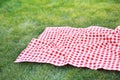 Red checkered tablecloth on green grass empty copy space,red picnic cloth food advertisement design Royalty Free Stock Photo