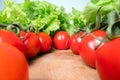 Red cheery tomatoes with lettuce leafs on top of wooden table background. Home grown vegetables, healthy eating lifestyle